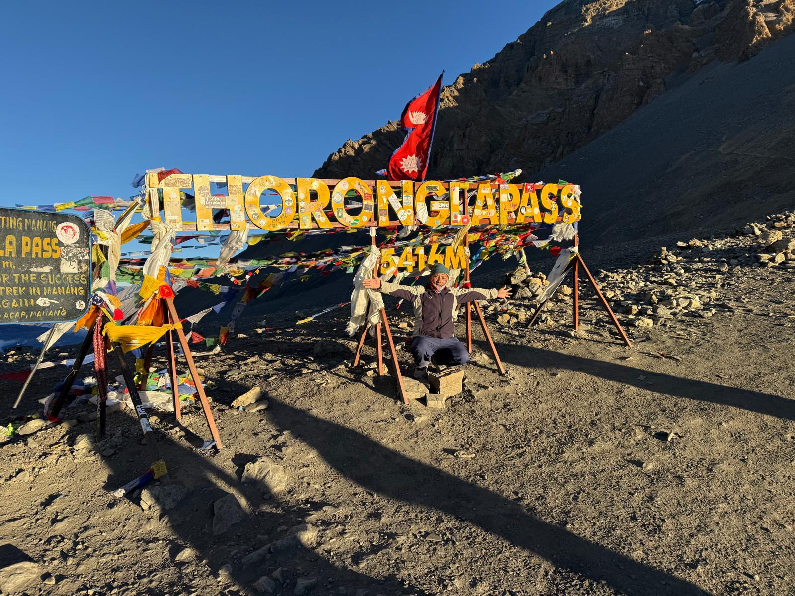 Trekker celebrating at Thorong La Pass 5416m Annapurna Circuit Nepal
