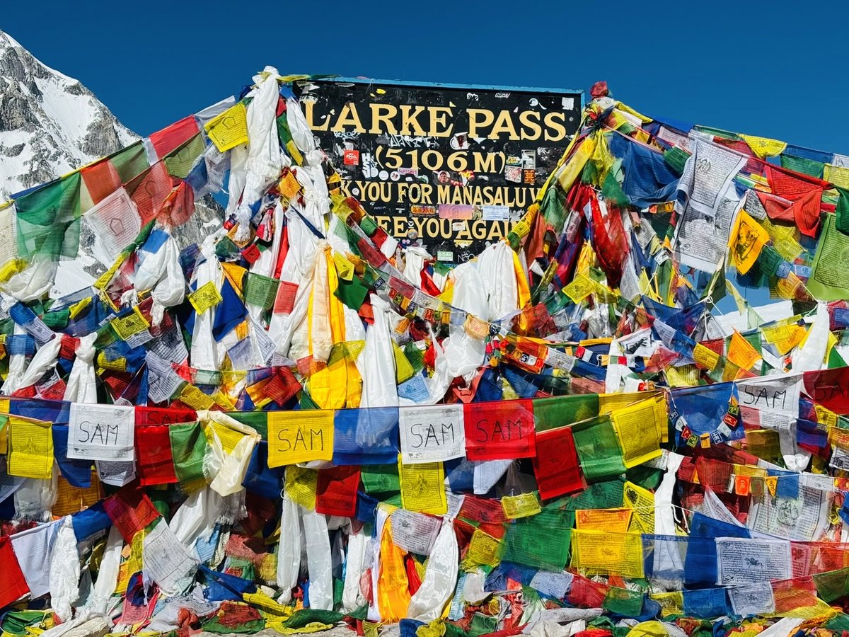 Larke Pass sign at 5,106 metres decorated with prayer flags on the Manaslu Circuit Trek